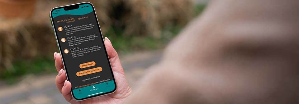 A person holding a phone that is displaying the Makers Trail app.